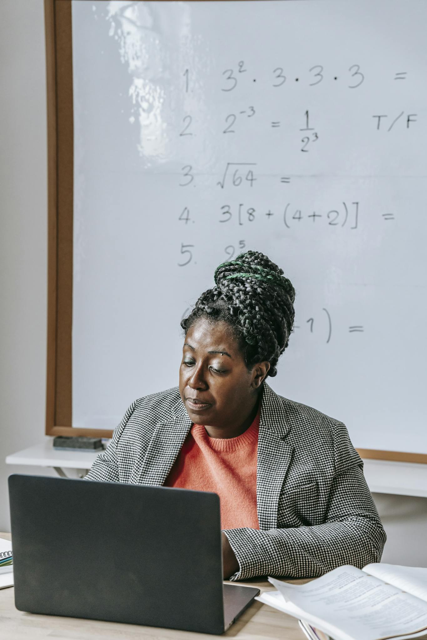 Intelligent African American female explaining difficult task online on netbook in classroom with whiteboard